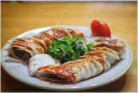 Adana kebab opgerold in een wrap met tomatensaus, hete roomboter en yogurt